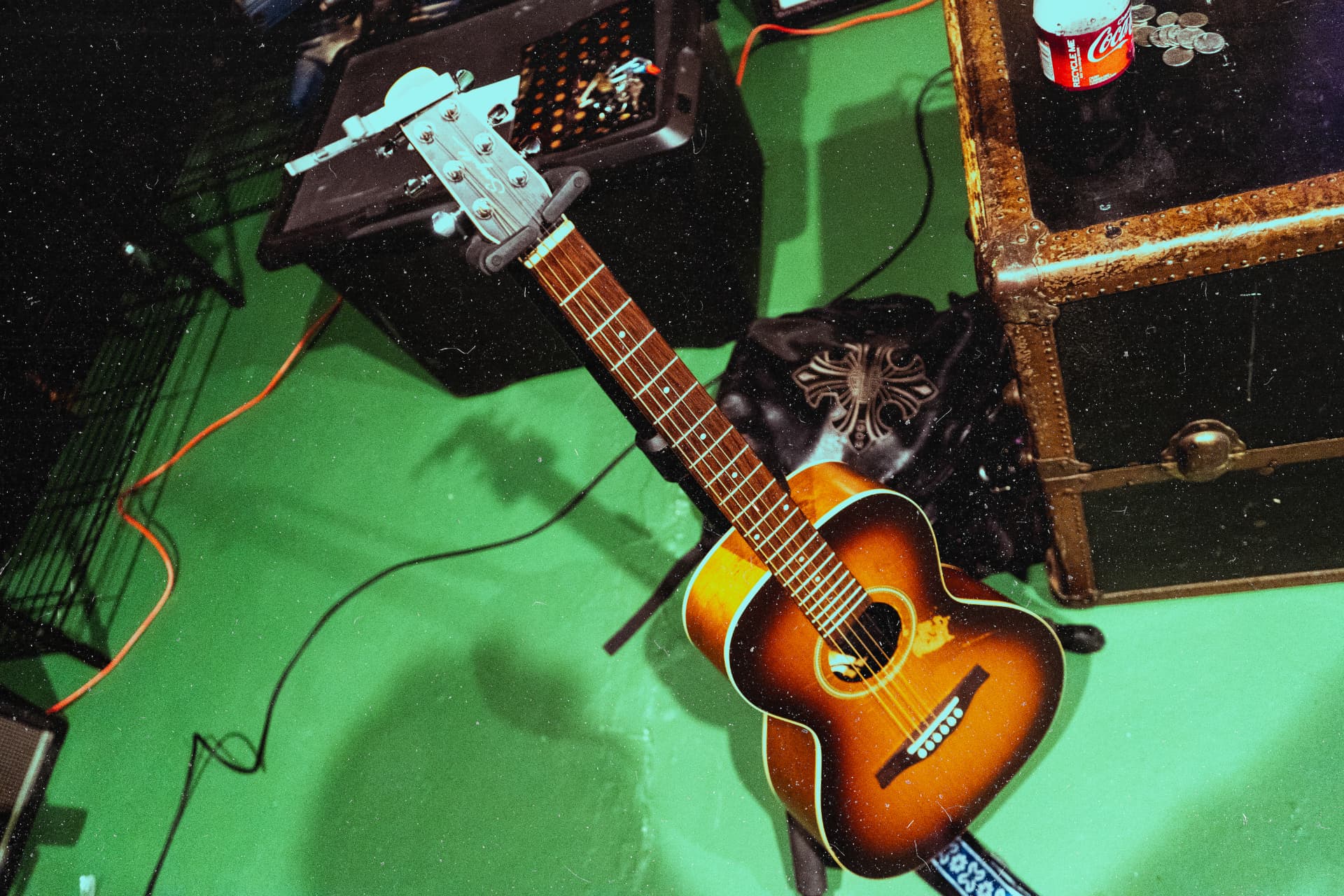 Acoustic guitar resting on the green studio floor